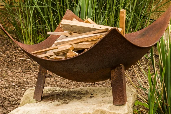 Rostige Feuerschale mit Brennholz